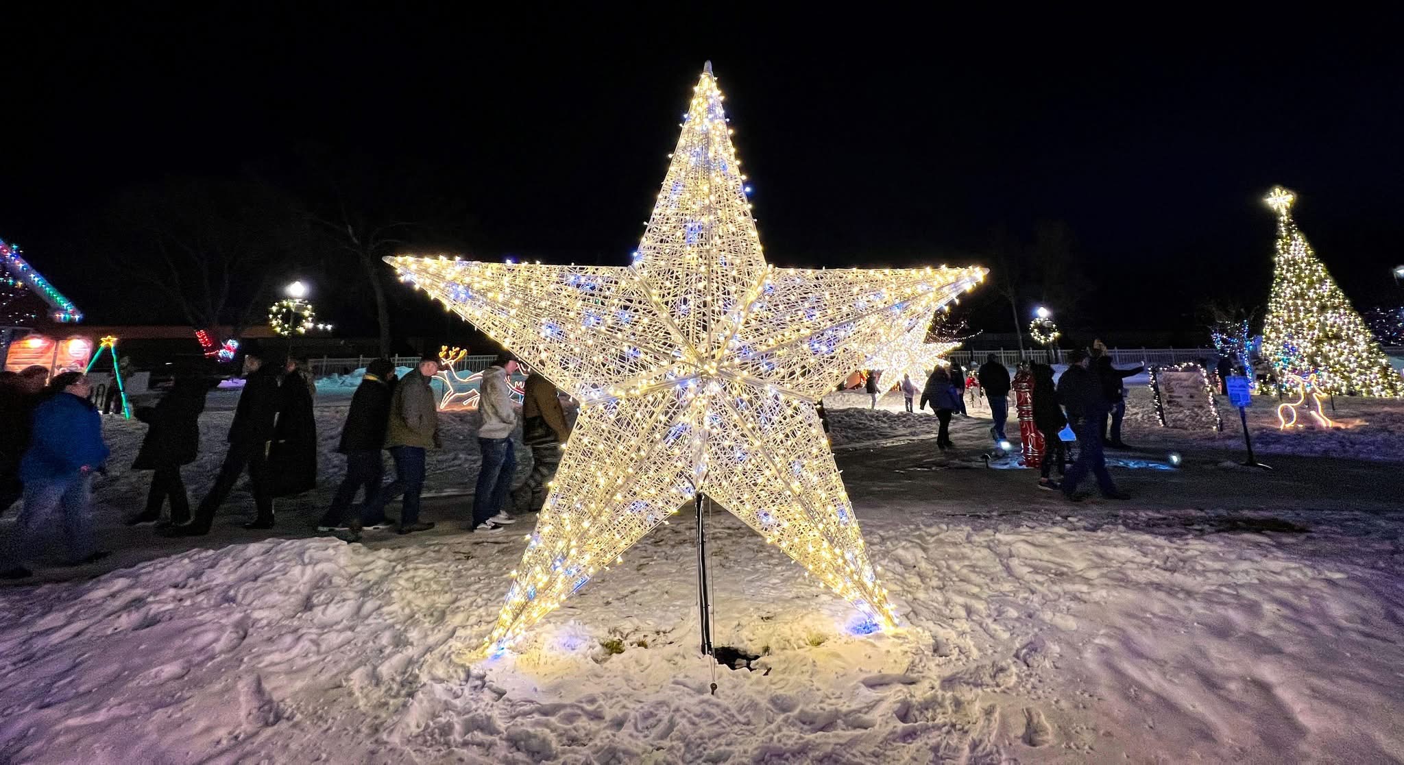 Illuminated hollow star sculpture installed on a snowy downtown plaza